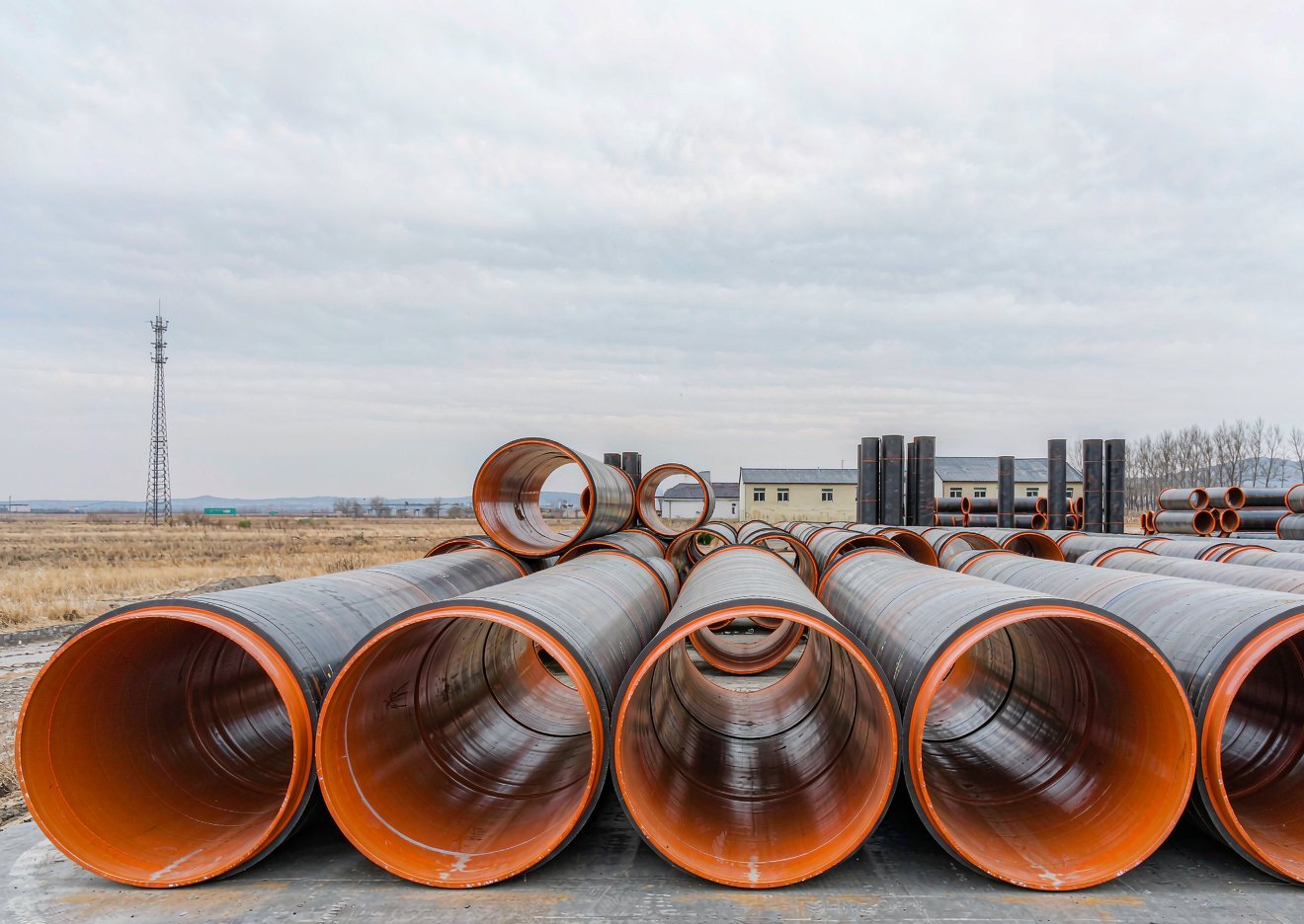 Large diameter clad pipes stacked in the yard with the stainless liner visible at the open ends